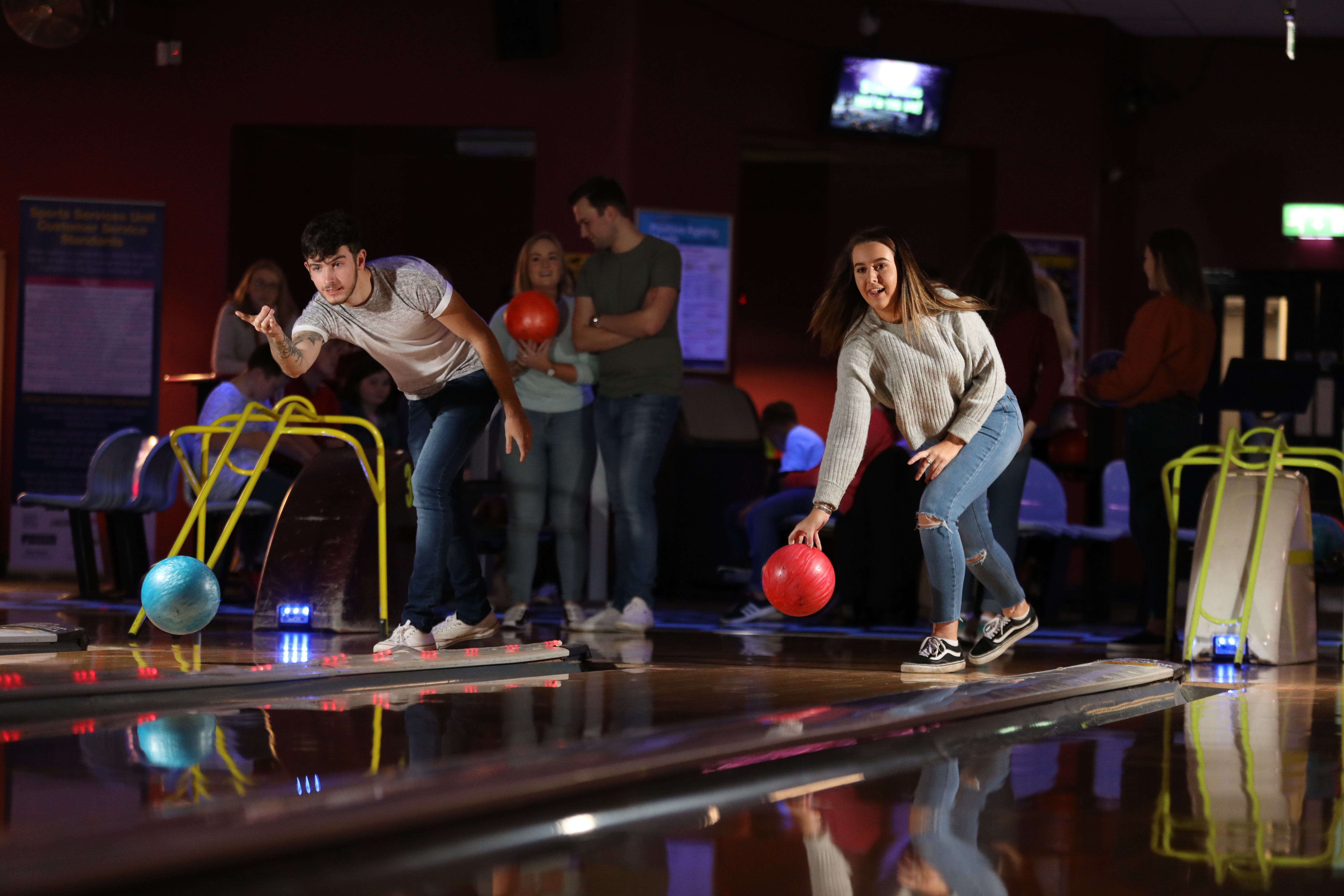 Two people bowling at dimly lit tenpin bowling alley 