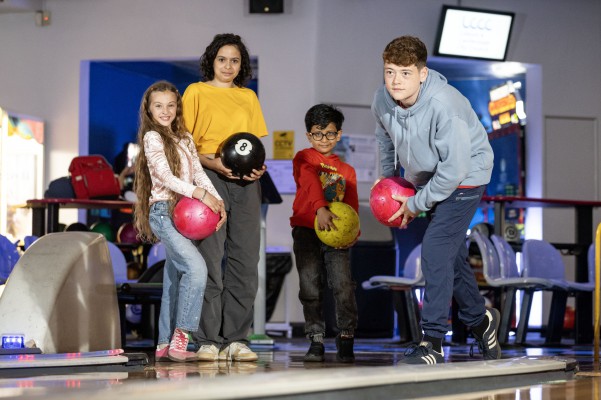 Two people tenpin bowling in dimly lit bowling alley